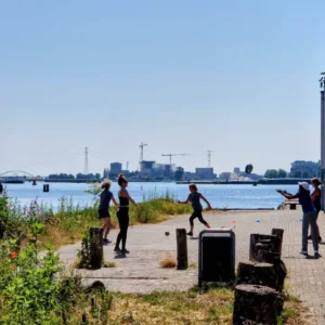 mensen bewegen aan op de stenen oever aan het 'IJ in Amsterdam