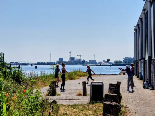 mensen bewegen aan op de stenen oever aan het 'IJ in Amsterdam